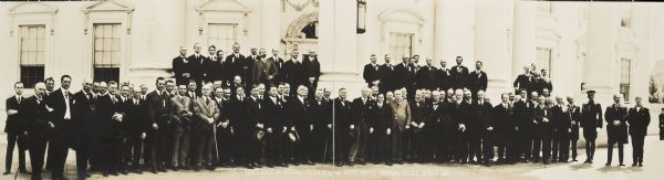 Panoramic group portrait of the Conference on National Defense, taken on the steps of the White House.