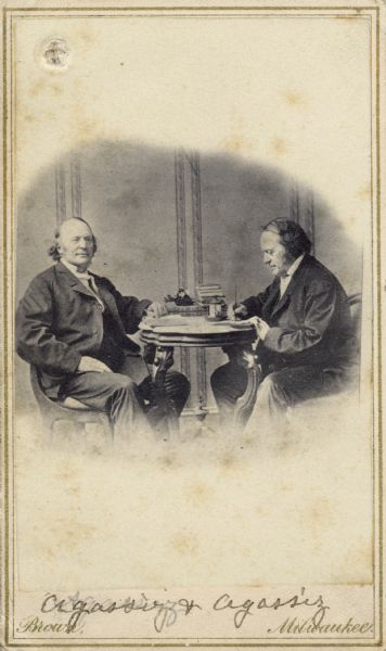 Carte-de-visite photomontage double portrait of the geologist and zoologist, Jean Louis Rudolphe Agassiz (1807-1873). Founded the Museum of Comparative Zoology in 1860. Founding member of the National Academy of Sciences in 1863. Shown simultaneously sitting and writing at a table. Handwritten inscription at the bottom reads, "Agassiz and Agassiz."

