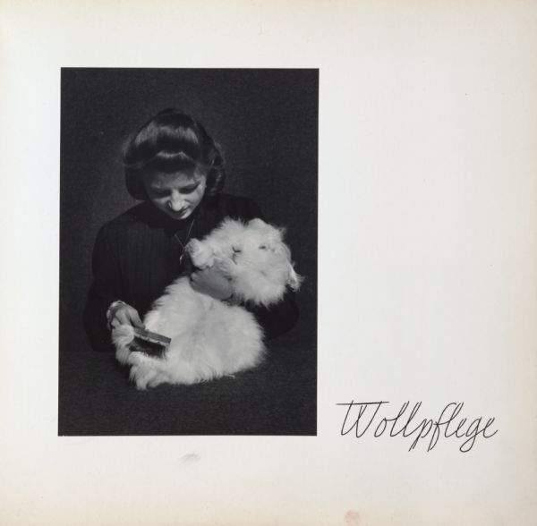 Woman holding angora rabbit in her arms and grooming it with a brush. Text on page says, "Wollpflege".