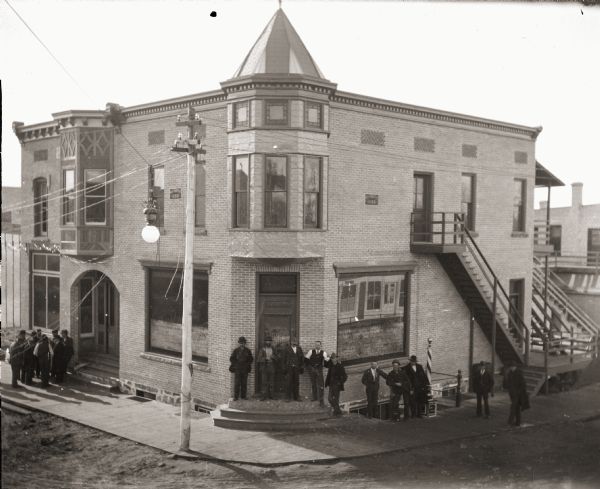 Elevated view of group of men posing in front of the newly built W.H. Murphy building on the corner of Main Street and West Montello Street. Photograph was taken after completion of the building in 1899.