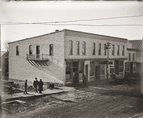 Elevated view of group of men standing in front of construction site, near a newly completed building on Main Street, near the intersection of West Montello Street.