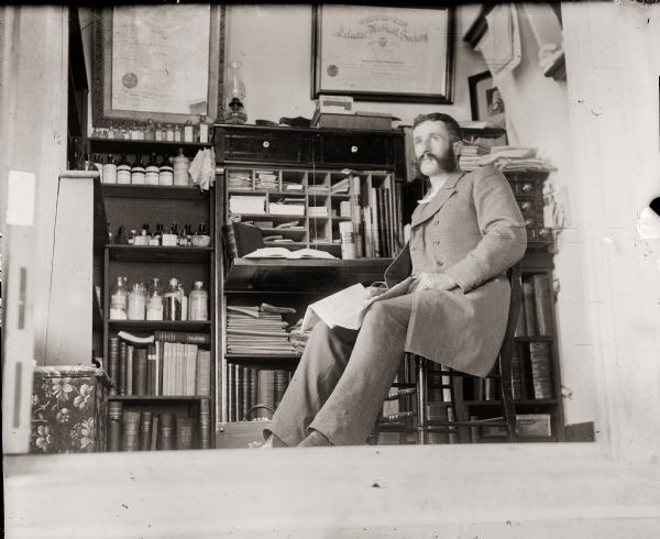 Self-portrait of Dr. Edward A. Bass sitting in his Pratt house office.
