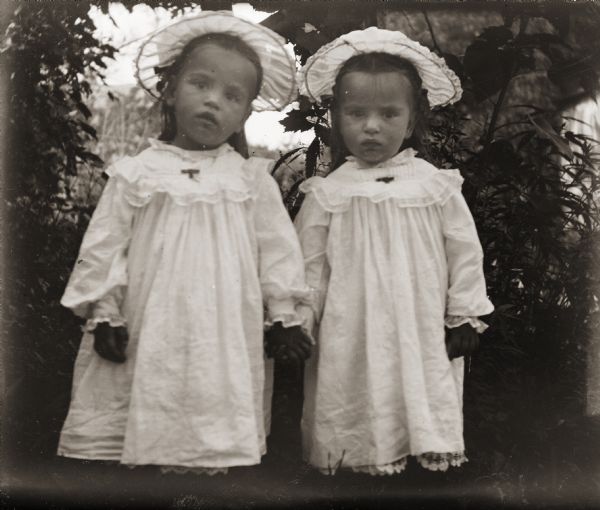 Two girls, identified as the McLean Twins, holding hands.