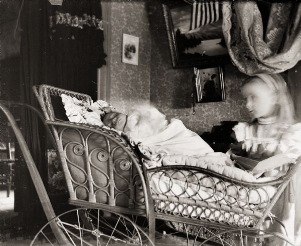 Cary Bass, son of the photographer, asleep in baby carriage with his sister Everetta standing nearby.