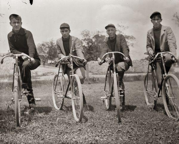 Four young men posing with their bicycles.