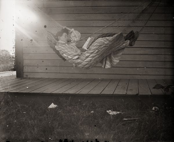 Ada Bass reading a book while lying in a hammock.