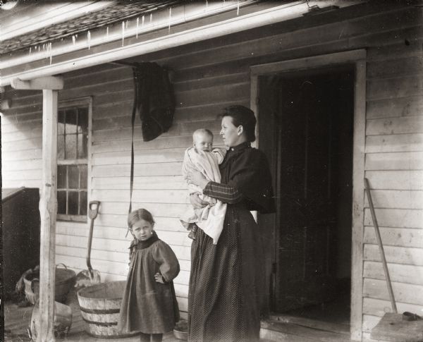 Mrs. McInges and children posing on porch of house.