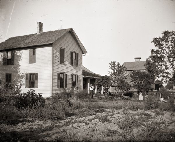 The Bass farmhouse, originally owned by the photographer's father, Isaac Bass. Pictured are the photographer's mother, Lorinda Bass, brother Frank Bass holding his son Floyd, sister Rhoda, and children Cary and Everetta Bass.