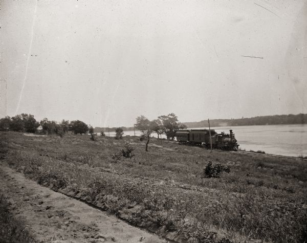 Wisconsin Central train running through country along the shoreline, possibly Buffalo Lake.