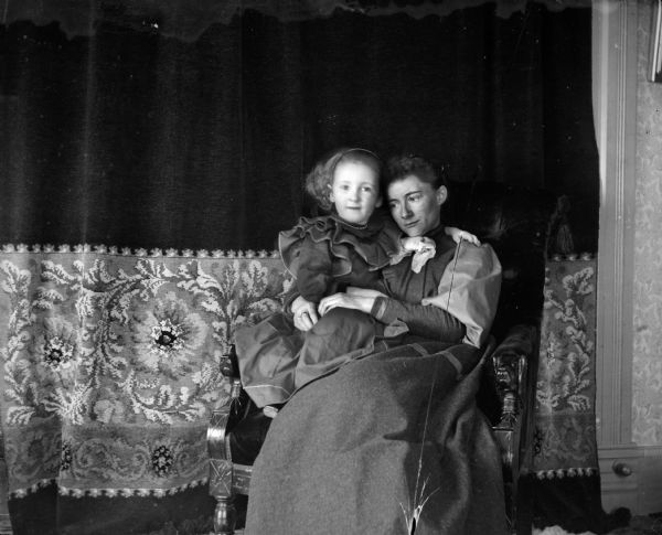 Ada Bass with her daughter Everetta on a chair in front of a curtain.