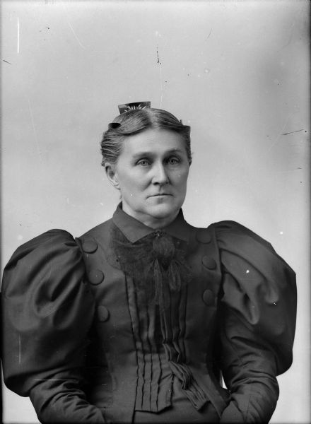 Studio portrait of an unidentified woman in a fancy dress and wearing a decorative comb in her hair.