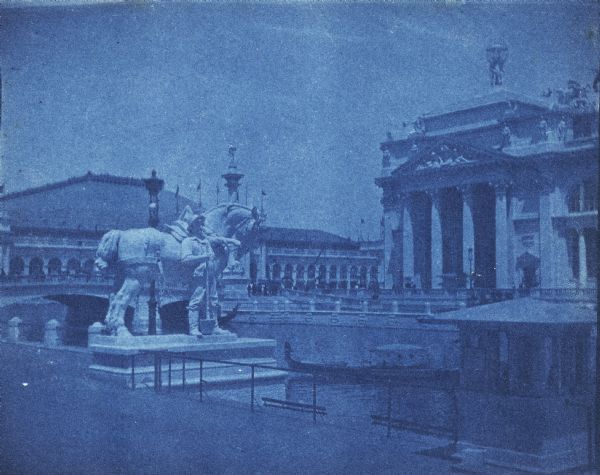 A cyanotype view of the Agriculture Building (right) and Manufactures and Liberal Arts Building (left) from the bank of the South Canal at the World's Columbian Exposition. A monumental statue of a horse and farmer are in the foreground. There is a gondola on the canal and a bridge on the left.