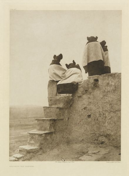 The original caption reads: "A group of girls on the topmost roof of Walpi, looking down into the plaza." An informal group portrait of Hopi women.