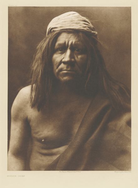 The original caption reads: "A representative type of the Mohave men." From "The North American Indian," the multi-volume set in which Curtis attempted to document all of the North American Indian tribes. The entire 20 volume set and accompanying portfolios, consist of 2,232 portfolio and bound volume gravures and text, cost $1,500,000 to produce (272 total editions). At least half of the funding came from J.P. Morgan and his son, Jack, by way of grants. A portrait of an Indian man, his body half-covered by a cloth.