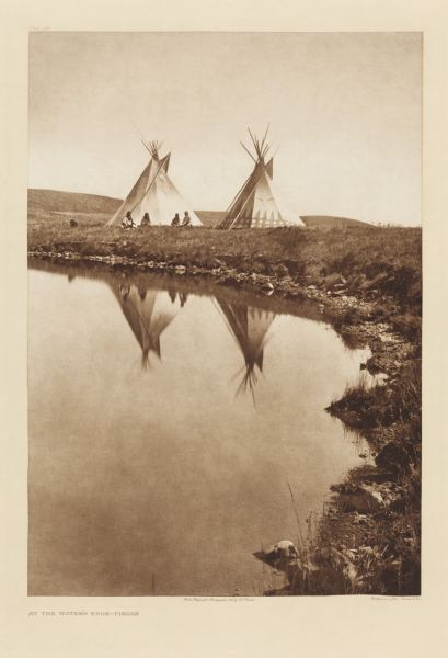 American Indians sitting near dwellings at the edge of a body of water.