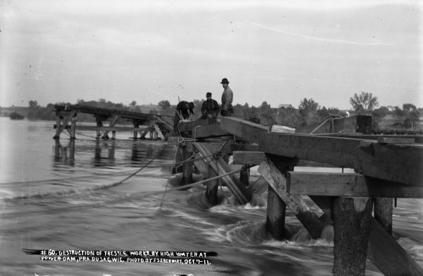 Workers attempt to secure the trestle against high water on the Wisconsin River during construction of the power dam.
