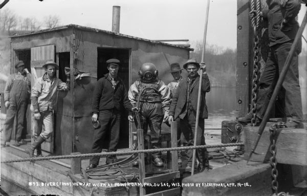 A diver posing with other workmen at the power dam construction site prior to assessing underwater damage.