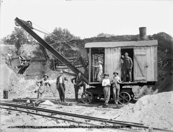 Workers and a boy, Edgar Walch, posing on and around a steam shovel in the quarry at Eagle View Bluff. Edgar's father, Engelbert Walch, owned the steam shovel. The gravel was used for the concrete for the dam. The narrow gauge track for the electric cars is in the foreground.