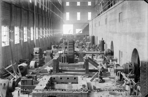 An interior view of the power house at the Prairie du Sac dam, showing assembly of the generators, identified by the manufacturer, the Allis-Chalmers Company, on castings.