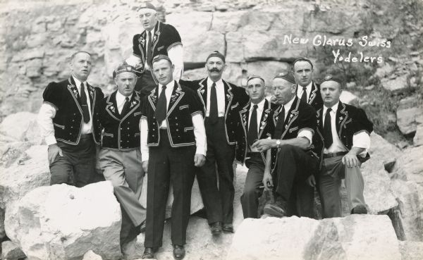 Outdoor group portrait of a group of Swiss yodelers in costume. The gentleman in the center has a distinctive moustache.