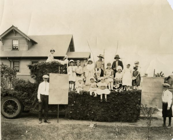 Children dressed as literary characters on a 4th of July float. Some children hold banners promoting the library.