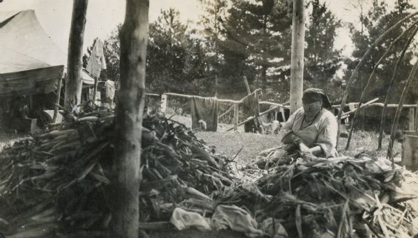 Winnebago (Ho-Chunk) woman husking corn.