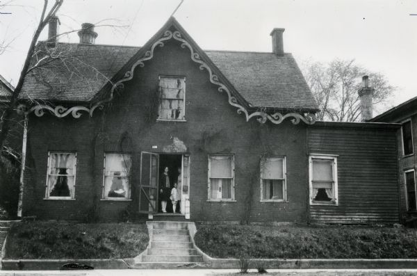 The Waldecker house, built by Mr. Gruenewalt in about 1853, at the corner of Jackson and Merchant Streets (120 Merchant Street). People are standing just inside the open front door.