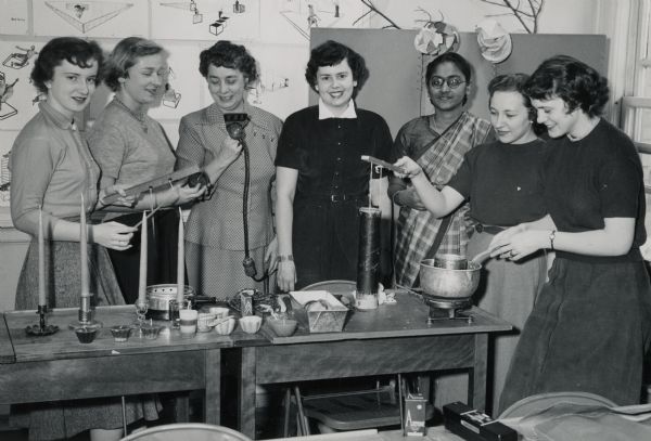 Aline W. Hazard (holding WHA microphone), Director of the Homemakers' Program, WHA-Radio and TV, with a University of Wisconsin-Madison Home Economics class. The women are making candles. One of the students is from India.