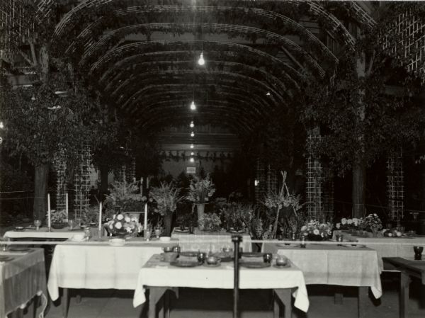 Interior view of the Fruits and Vegetables Building at the Wisconsin State Fair, showing the dining room and the tables decorated with lavish floral displays.