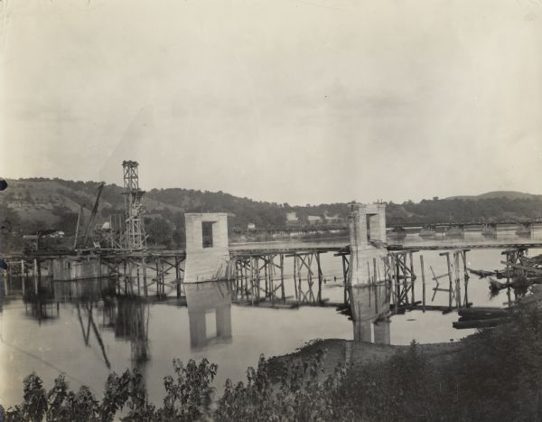 Construction of the new Wisconsin River Bridge at Prairie du Sac taken by Melvin Diemer for the Wisconsin Goods Roads Association. The old toll bridge is visible in the background.