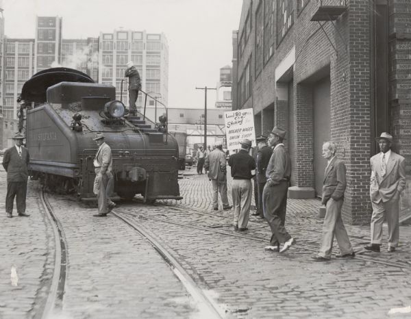 Members of the United Packinghouse Workers Local 80 picketing the Campbell Soup Company plant. The union had walked out as a result of wage, union shop, and seniority disputes.  In this photograph they have just prevented the railroad engine from entering the Campbell Company plant.