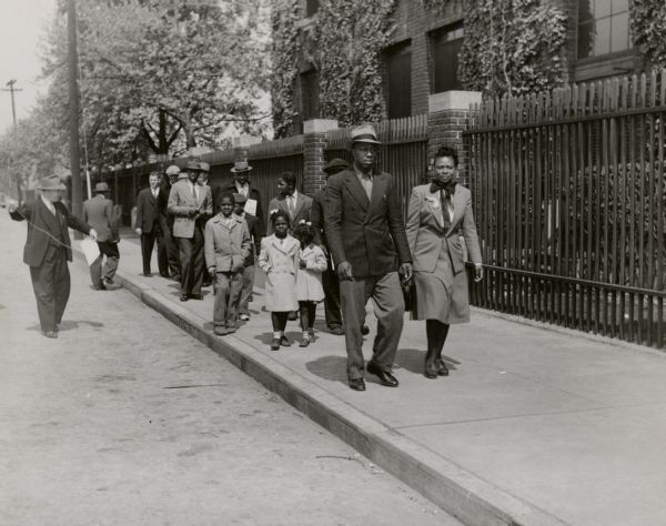 Striking members of Packinghouse Workers Local 392 in Baltimore getting ready for Children's Day on the picket line. Frank McCarty, of the UPWA, is about to attach a sign that expressed the union's wage demands: "My Daddy needs 24 cents to Buy me more Milk." The union was on strike against the American Sugar Refining Company.