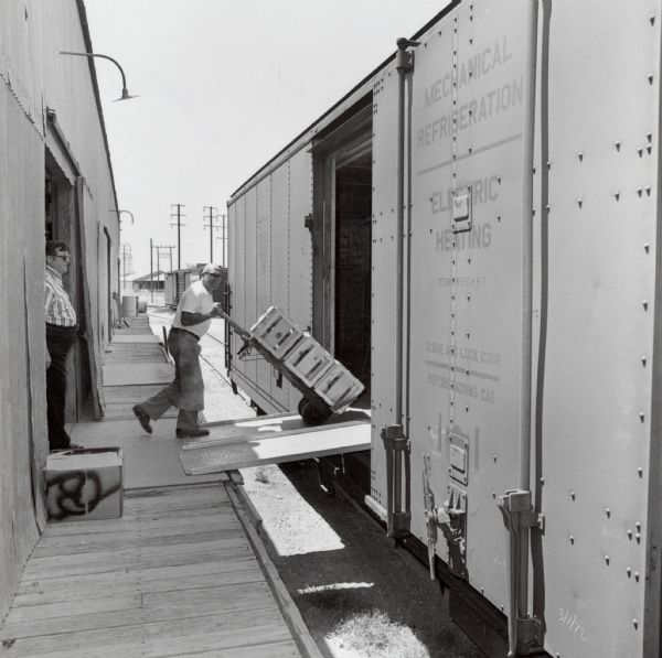 An unidentified worker, probably in California, loading crates of melons onto a refrigerated railroad car.