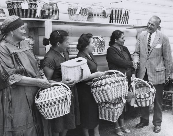 Jack Olson, Republican Party leader and owner of the Olson Boat Company of the Wisconsin Dells, with a group of Native American women who were winners in a basket weaving contest.