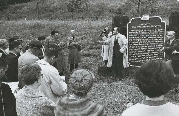 Senator Hubert Humphrey of Minnesota campaigning for the presidential nomination in southwestern Wisconsin.  Humphrey stands at the historical marker in Coon Valley which commemorates the first watershed erosion project in the nation. Standing at the left of the photograph (wearing eyeglasses, but no hat) is Patrick J. Lucey, then chairman of the Wisconsin Democratic Party. During the 1950s when Wisconsin had two Republican senators, Wisconsin Democrats looked to Humphrey as their senator.