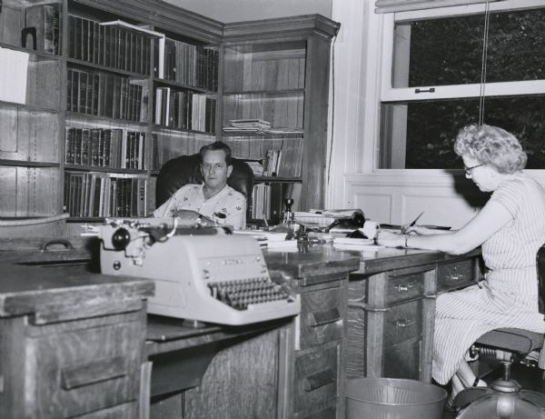 Wisconsin Historical Society archivist Jesse Boell, later the archivist of the University of Wisconsin, seen in his office on the third floor of the Historical Society building. The woman in the photograph is unidentified.