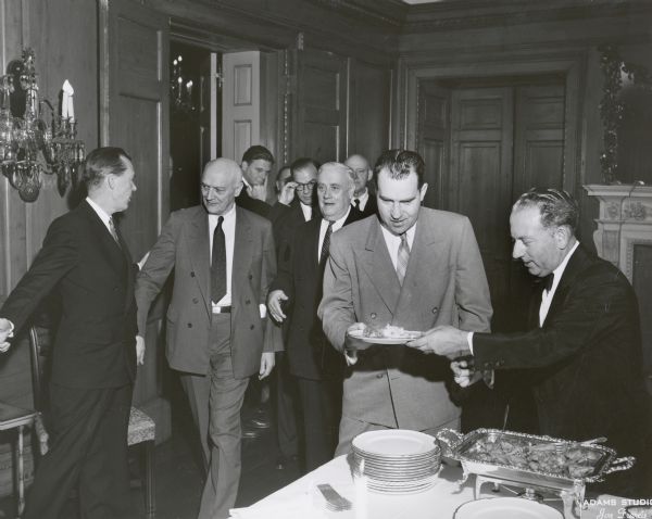 Vice President Richard M. Nixon in a buffet line in Washington, D.C., with a group of dignitaries behind him. Immediately behind Nixon's right shoulder is Wisconsin Senator Alexander Wiley.