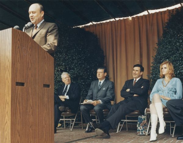 Secretary of Defense Melvin Laird of Wisconsin, speaking at a Savings Bond rally at the Pentagon.  On the platform is actress Ann Margaret wearing a short skirt and high boots, newsman Frank Blair, and Secretary of the Navy John Chafee, next to the actress.