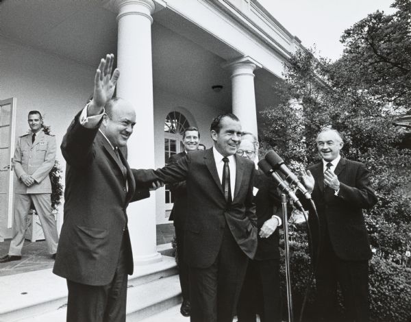Standing by President Richard Nixon, Secretary of Defense Melvin Laird waves to a White House Rose Garden audience during an event for William H. Brown, who is standing on the right.
