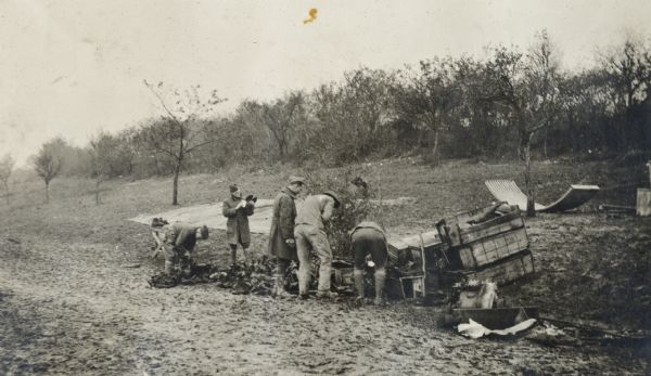 While engaged in road construction near Aubreville, France, the 310th Engineers came upon this scene and helped themselves. Photographer Victor Morris labeled the picture "getting an extra pair of boots."