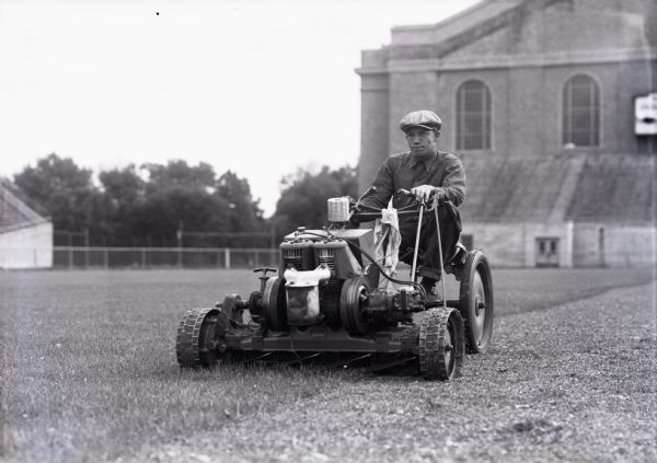Cutting the grass with a large lawn mower near the University of Wisconsin-Madison Field House (currently Camp Randall Stadium).