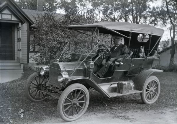 George Fortune of River Falls sitting in his new car, with his dog in the back seat.