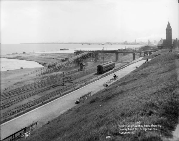 Overlooking the Chicago and North Western railroad depot from Juneau Park bluff. Caption on glass plate reads: "Extention [<i>sic</i>] of Juneau Park, showing runway built for dump wagons".