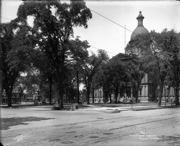 Courthouse Square (now Cathedral Square) showing Milwaukee County Courthouse from E. Wells and N. Jackson Streets. Caption on glass plate reads: "Court house [<i>sic</i>] square".