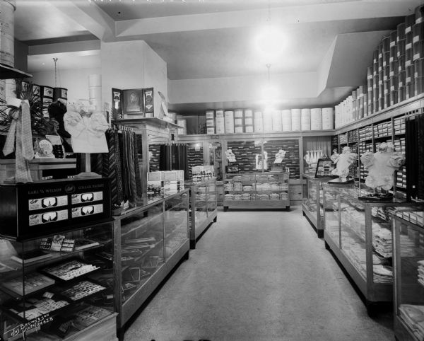 Kramer's Clothing shop, located on the north side of W. Wisconsin Avenue between N. 5th and N. 6th streets. Inside, displays of men's clothing merchandise are neatly organized.