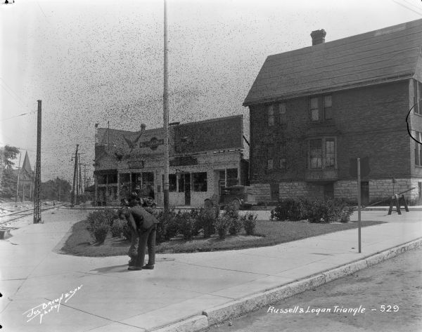 Looking southeast on S. Kinnickinnic Avenue at E. Russell Avenue and S. Logan Avenue in the Bay View neighborhood. Trinity (now the Bay View) Methodist Church is in the background on the left. Caption on glass plate reads: "Russell and Logan Triangle".