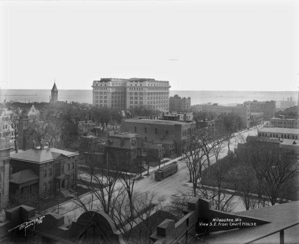 Elevated view southeast from the courthouse at E. Kilbourn Avenue and N. Jackson Street. The Northwestern Mutual home office building and Chicago and North Western railroad depot are on the left. The clock tower and Lake Michigan are in the distance.