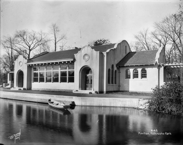 Pavilion at Kosciusko Park lagoon at W. Lincoln Avenue and S. 7th Street. A rowboat is floating in the lagoon.