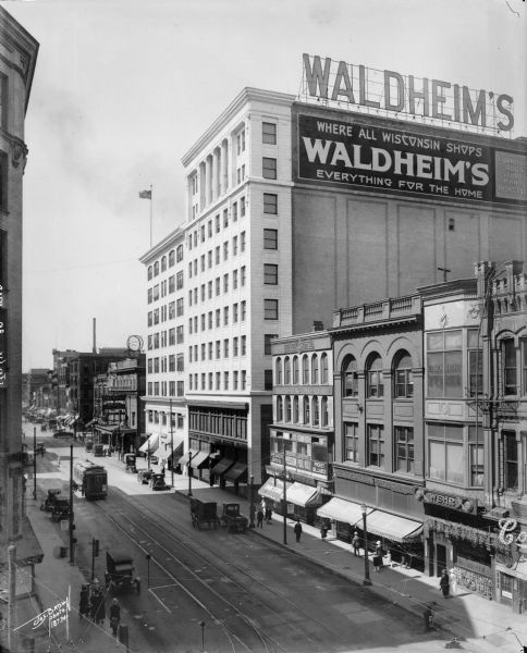 Elevated view of the Waldheim furniture building and surrounding commercial area on N. Plankinton Avenue, north of W. Wisconsin Avenue. The Waldheim Furniture building is in the center with the Merchant's and Manufacturer's Bank and Empress Theater to its left.