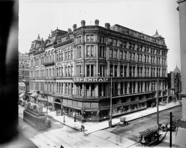 Elevated view of Espenhain's department store located on the northwest corner of N. 4th Street and W. Wisconsin Avenue. Pedestrians, horse-drawn vehicles, and a streetcar are on the adjacent streets.